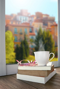 一杯热饮茶或咖啡和书籍躺在美丽的欧式建筑风格的窗前，让人放松