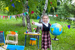 快乐的女学生小女孩抱着地球，微笑着，拇指