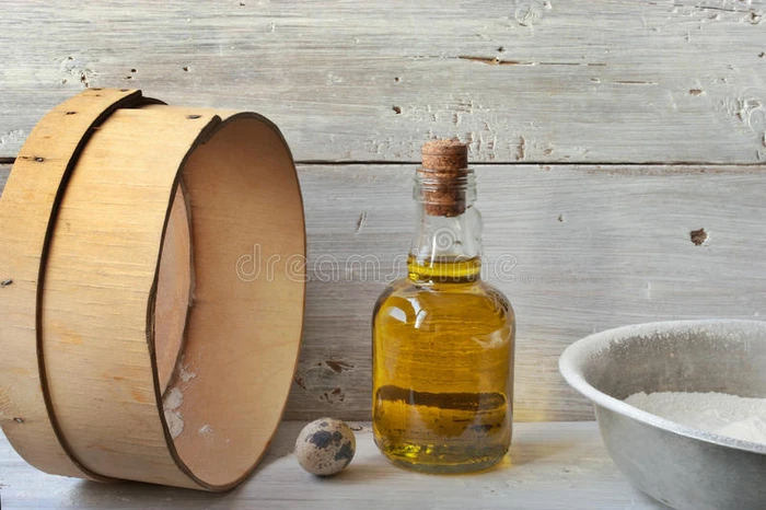 鸡蛋面粉和一瓶橄榄油在白色的木桌上