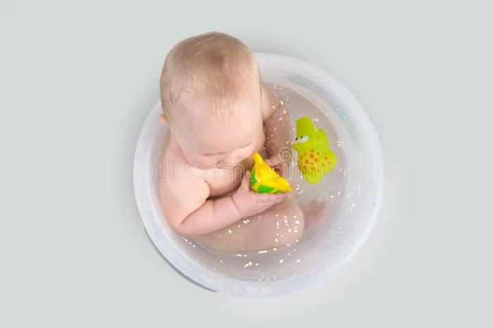 可爱的婴儿在透明的桶里洗澡玩t