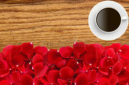 美丽的红色玫瑰花瓣和咖啡杯超过木材纹理