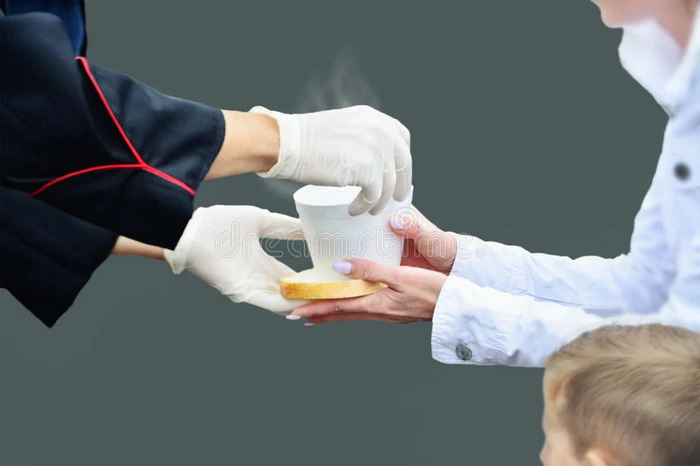 双手戴着白色手套给一个有孩子的女人一杯热汤