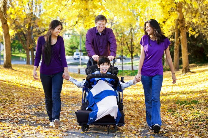 家庭带着残疾儿童在轮椅上行走在秋乐之间