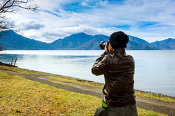 亚洲男人正在湖边拍照