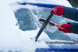 妇女的手使用刷子和清除雪从汽车和挡风玻璃