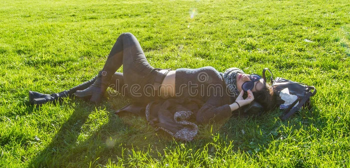 可爱的女孩躺在绿色的草地上在阳光下放松
