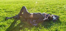 可爱的女孩躺在绿色的草地上，在阳光下放松