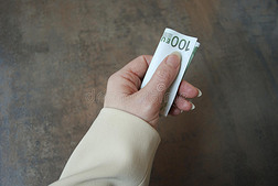 女性手握折叠货币钞票。