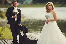 新郎钦佩一个漂亮的金发新娘站在一条河后面