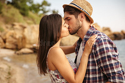 美丽的年轻夫妇站在海滩上接吻