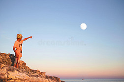 梦幻般的男孩用手指指着天空中的月亮