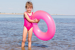 五岁的女孩穿着粉红色的泳衣站在河里游泳