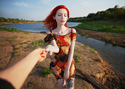 站在河的背景上穿着太阳裙的漂亮红头发女孩