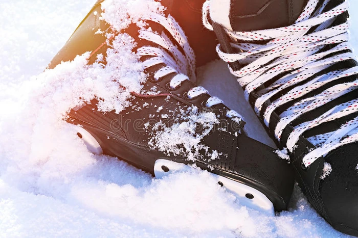 黑色曲棍球溜冰鞋躺在雪地和明亮的阳光下
