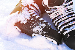 黑色曲棍球溜冰鞋躺在雪地和明亮的阳光下