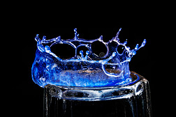 特写一个蓝色的皇冠状的水滴在玻璃上裂开