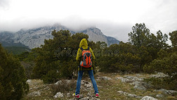 一个孤独的旅行者站在山上看着群山。 多云的黑暗天气。