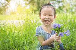 女孩微笑的在期间佃户租种的土地花和一次采用草地