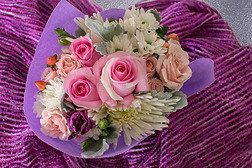 花束关于小的玫瑰和别的混合的花向紫色的织物.
