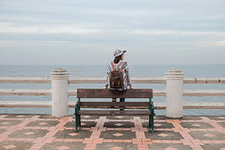 旅行背景年幼的女人坐向椅子和风景海看法