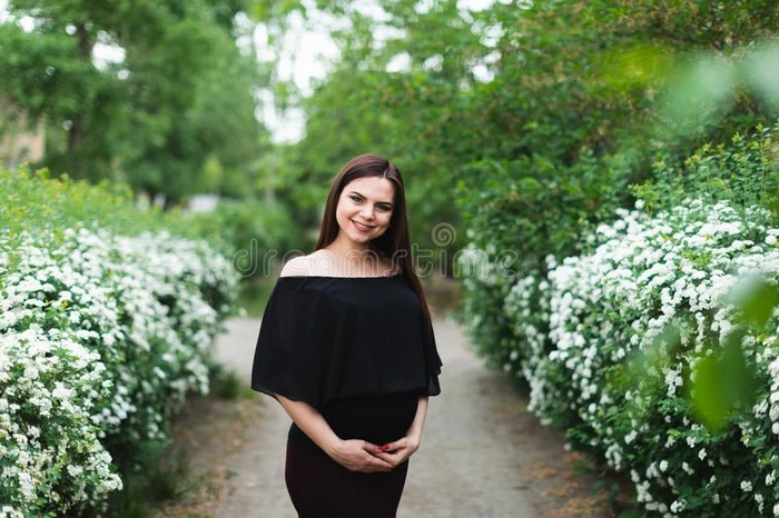怀孕的女孩在近处绣线菊类的植物灌木