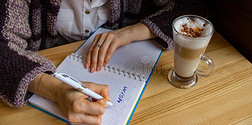 年幼的女人文字希望清单采用敞开的笔记簿采用咖啡馆.新的年