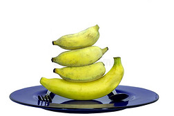 大的黄色的香蕉和蓝色盘和勺,餐叉向白色的后面