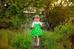 小的女孩走采用绿色的花园采用和煦的：照到阳光的一天