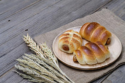 香肠面包和小麦耳和麻袋向木制的背景
