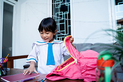 小孩使人疲乏的学校制服放det.一些书采用向她背包