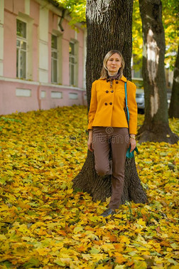 亚麻色的女人使摆姿势采用一秋大街和红色的一d黄色的树叶